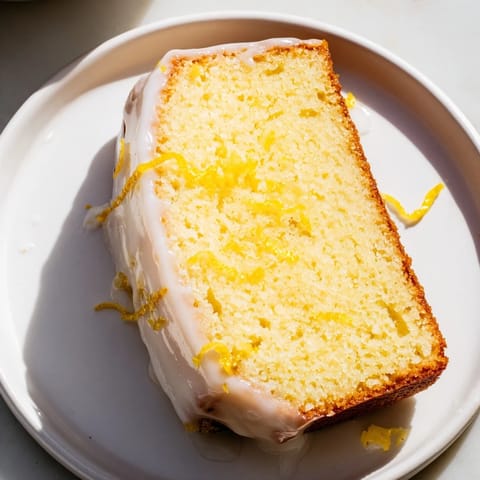 Golden-crusted Lemon Pound Cake slice, drizzled with glistening lemon glaze, ready to serve and enjoy.