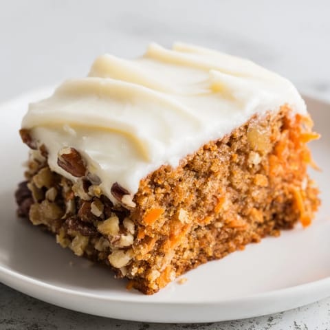 This layered carrot cake showcases a generous swirl of cream cheese frosting, ready to eat.