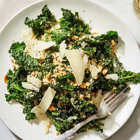 Garlic Parmesan Kale Salad presented in a white bowl, showing tender kale leaves, rich dressing, and crunchy panko topping.