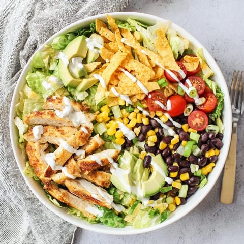 This easy Crunchy Taco Chicken Salad features colorful Tex-Mex ingredients, including shredded cheese and green onions, served in a bowl for a satisfying, gluten-free main dish meal.