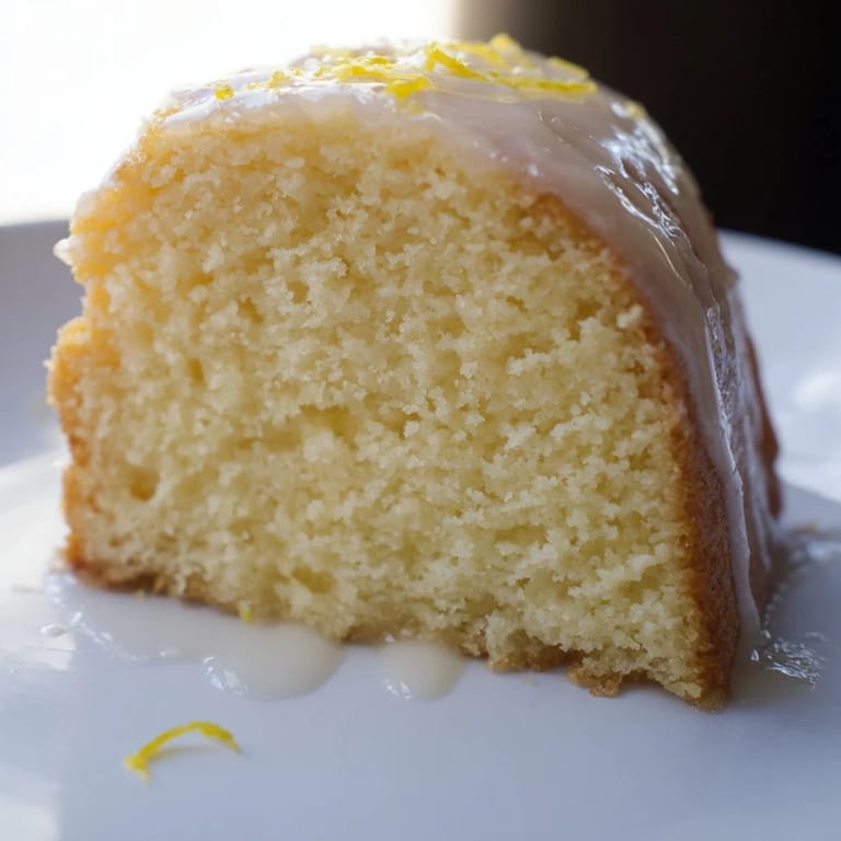 Moist and flavorful homemade Lemon Pound Cake, perfect for a cozy afternoon treat alongside a warm drink.