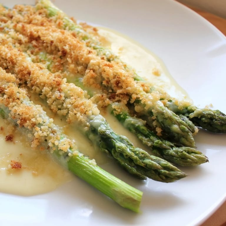 A close-up of baked Asparagus Casserole, showcasing the tender asparagus and golden breadcrumb topping.