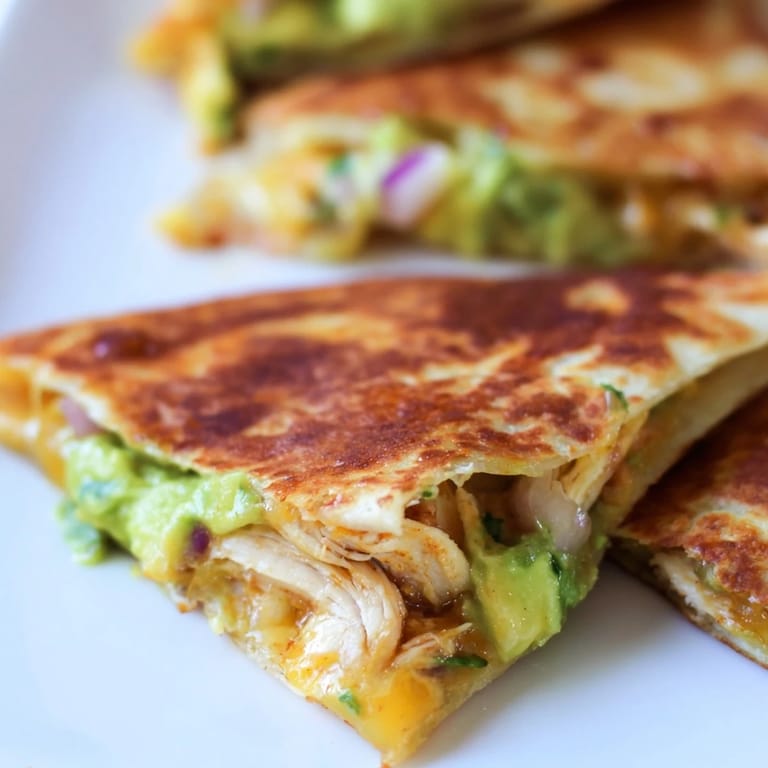 A close-up of a Chicken Avocado Quesadilla on a plate, garnished with cilantro and served with salsa.