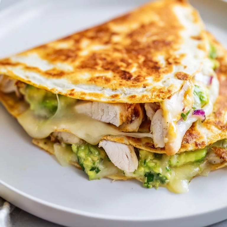 Freshly cooked Chicken Avocado Quesadilla slices revealing juicy chicken and gooey melted cheese filling.