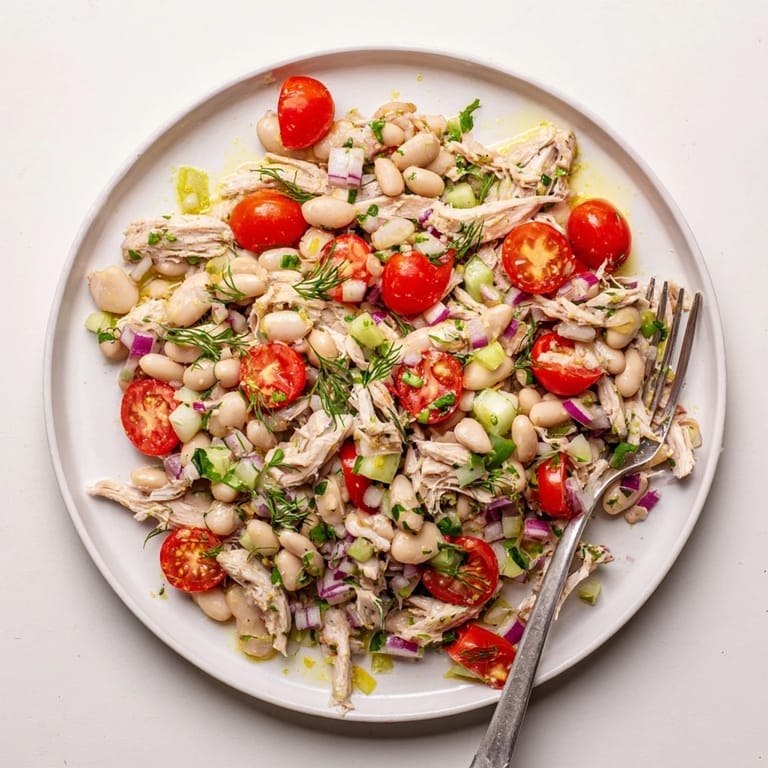 Perfectly chilled for a summer picnic, this protein-packed Lemony White Bean Chicken Salad showcases shredded chicken, white beans, and a bright lemon vinaigrette in a rustic wooden bowl.