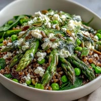 A close-up of the Spring Green Bowl, with bright peas and asparagus over quinoa, topped with seeds and a lemony dressing.