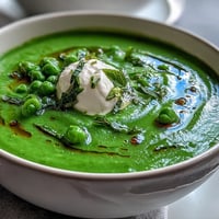 Spring pea soup with whipped ricotta, vibrant green and creamy topping.